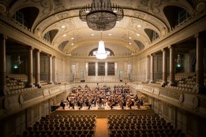 A picture of a music group in Switzerland performing on stage with empty audience seats