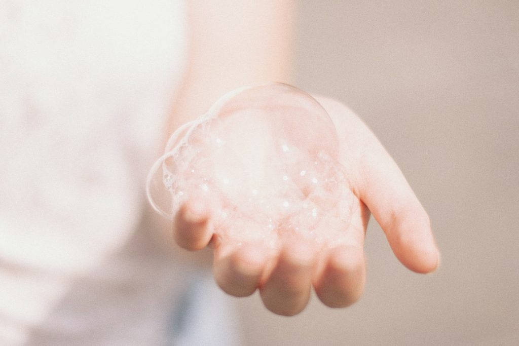 A picture of a person holding soap bubbles on their left hand.