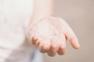 A picture of a person holding soap bubbles on their left hand.