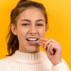 A woman holding a tooth guard by her mouth to promote dental health.
