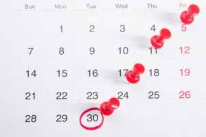 A picture of a calendar with red tacks tacked onto specific dates