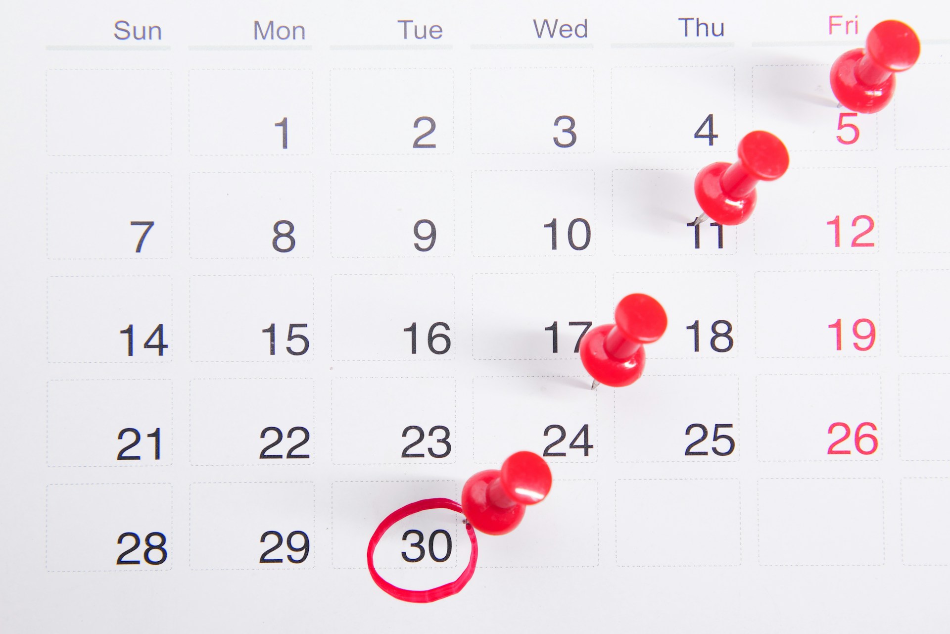 A picture of a calendar with red tacks tacked onto specific dates