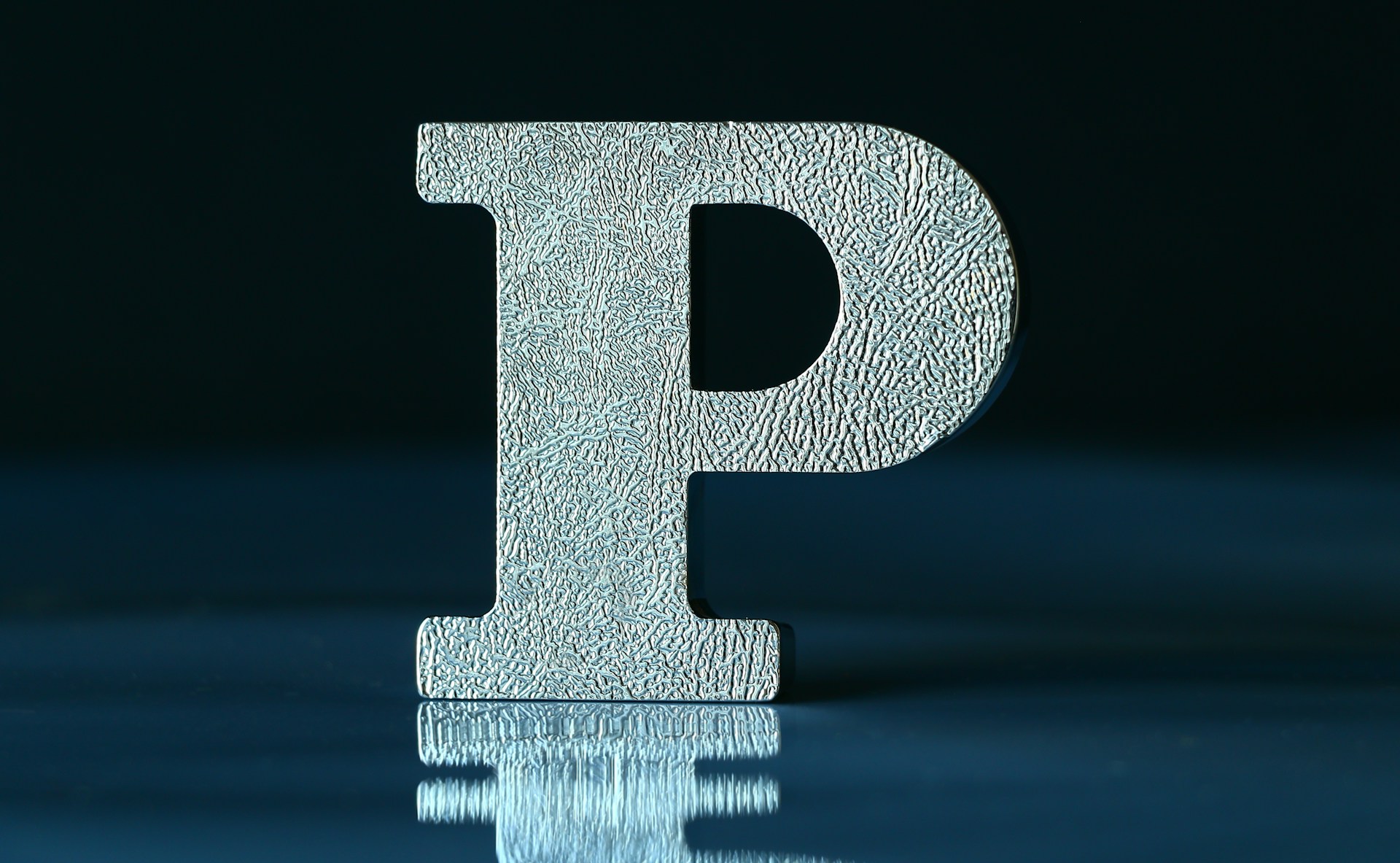 A Silver P resting in front a dark blue background
